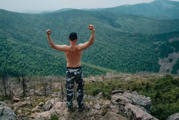 A hiker on top of a mountain enjoys the aerial view while raising his hands above the clouds Mount Falaza