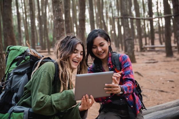 Hiker using tablet while relaxing in the pine wood forrest