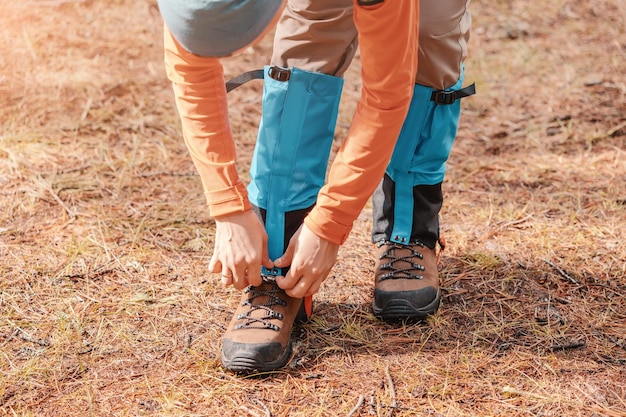 Hiker wears gaiters over trekking boots to protect against water insects and cold Clothing and equipment for backpacking and camping