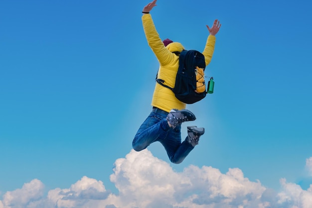 Hiker with backpack raising arms jumping on the top of a mountain - Successful man with arms up