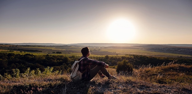 Hiker with backpack sitting on top of the mountain