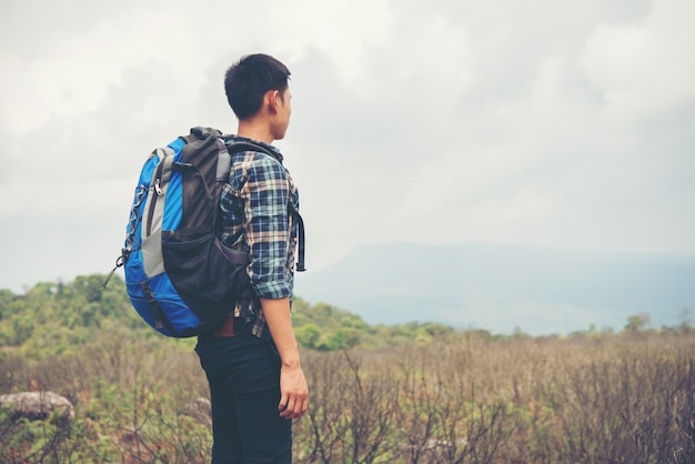 Hiker with backpacks standing on top of a mountain and enjoying nature view.