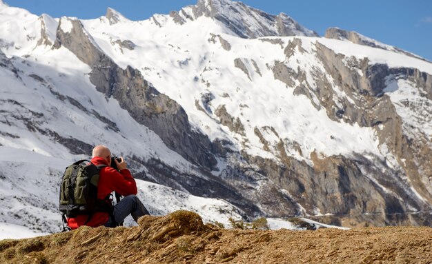 Hiker with camera and backpack taking picture of beautiful mountain