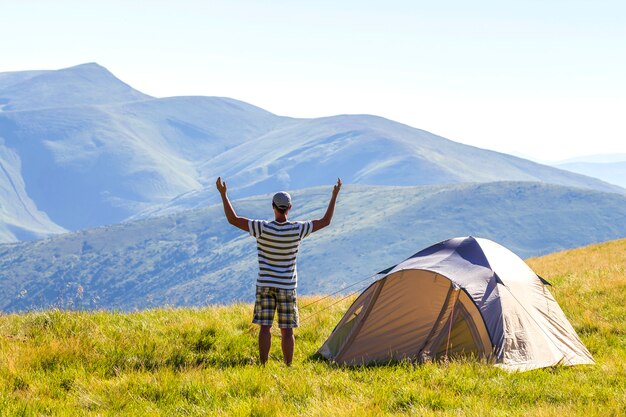 Hiker with raised hands in mountains.