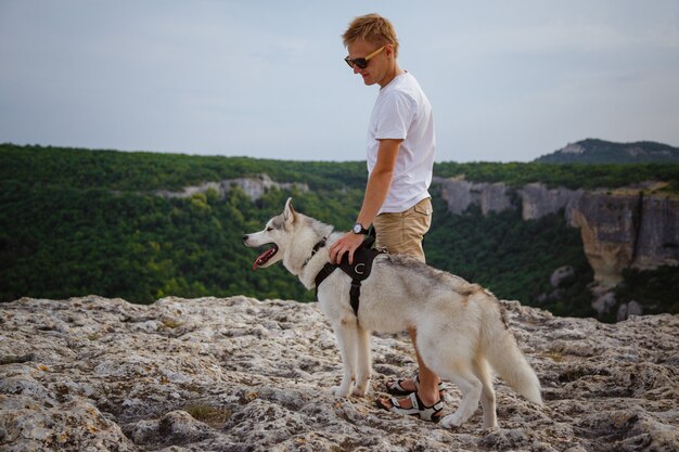 Hiker с собакой сибирской лайки смотря красивый вид в горах