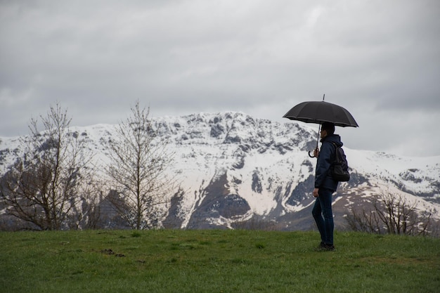 ベナスク渓谷の雨の日に山の景色を楽しむ傘を持ったハイカー