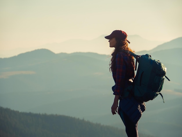 Donna escursionista con zaino in cima a una montagna