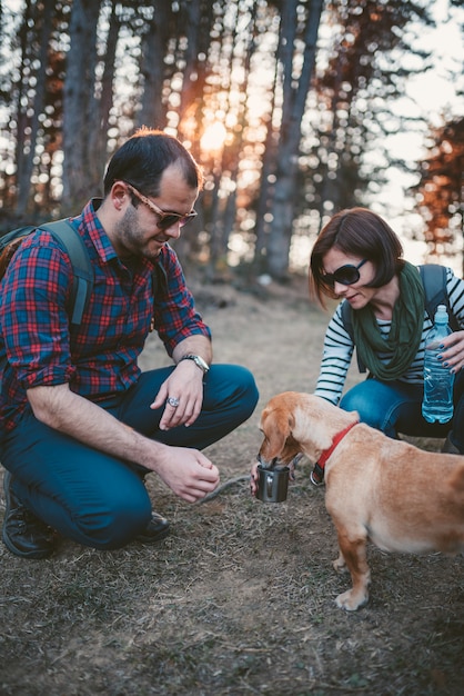 Hikers giving water to her dog in the forest