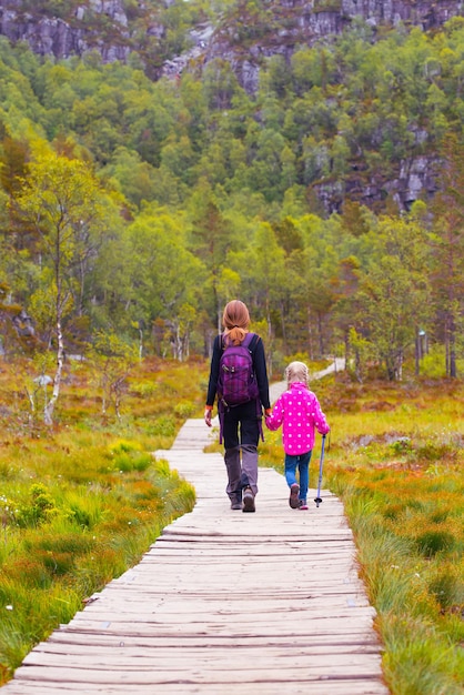 Hikers mom and daughter walk along the trail through the woods on  Preikestolen, norway