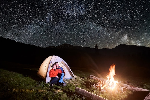 夜のキャンプファイヤーと観光テントの近くのハイカー
