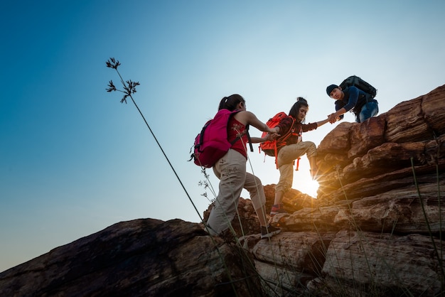 Hikers walking with backpack on a mountain at sunset. traveler going camping. travel concept.