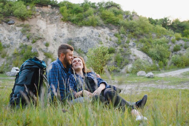 Hikers with backpacks relaxing on top of a hill and enjoying view of sunset