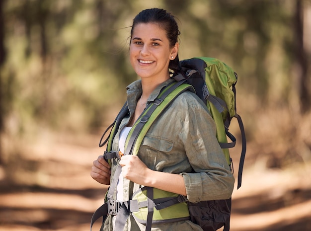 Hiking backpack and woman in forest portrait for journey travel and adventure in nature with sports fitness and wellness gear Woods trees and nature athlete smile walking or trekking outdoor