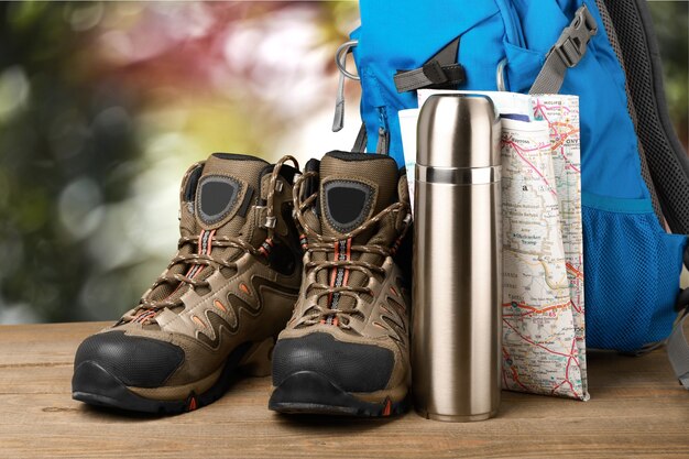 Hiking boots, backpack and map  on background