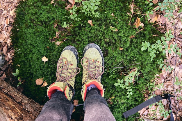 Hiking boots in outdoor action. top view of boot on the trail. close-up legs in jeans and sport trekking shoes on rocky srones of mountain river waterfall