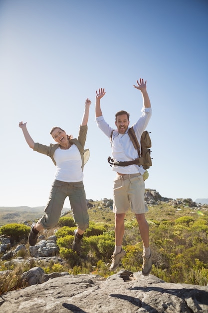 Hiking couple jumping and cheering on rocky terrain