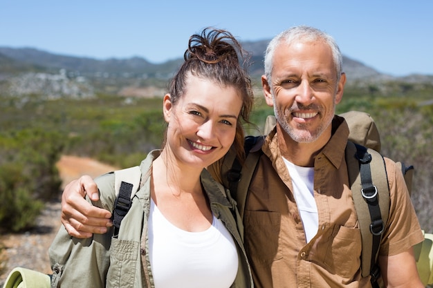 Hiking couple smiling at camera on mountain trail 
