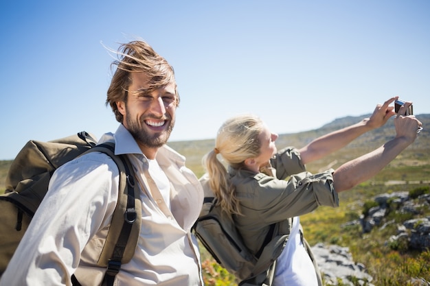 Hiking couple standing on mountain terrain taking a selfie