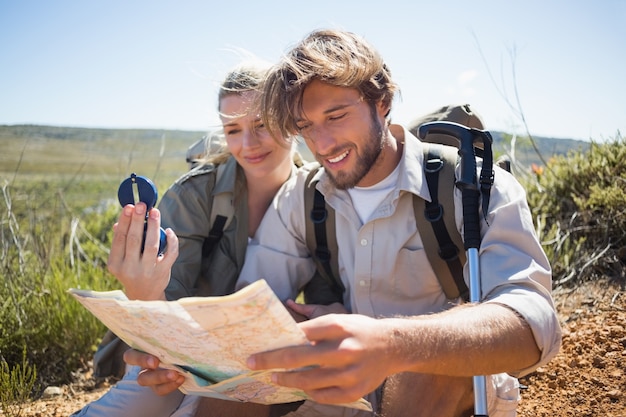 Hiking couple taking a break on mountain terrain using map and compass