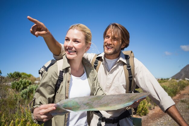 Hiking couple walking on mountain terrain looking at map