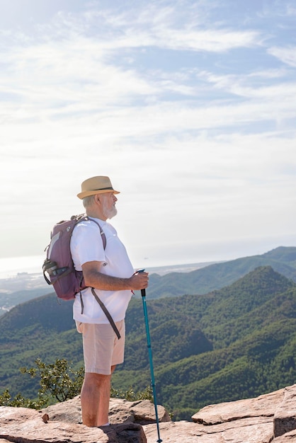 Hiking in the mountains older traveler with backpack hiking in\
the mountains active lifestyle concept in retirement