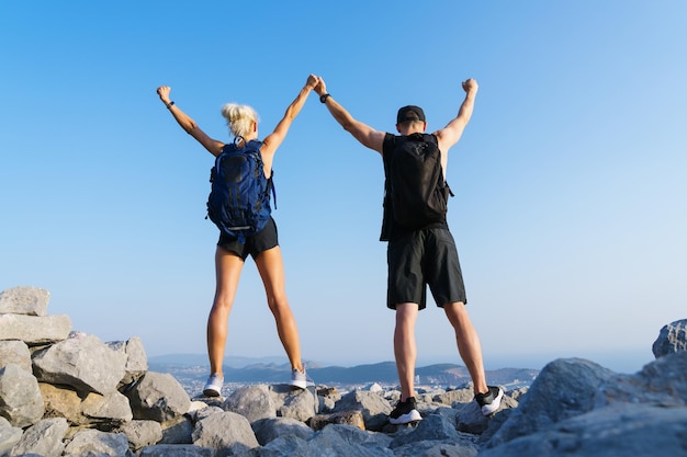 Hiking in the mountains A woman and a man with their hands raised on top of a mountain The joy of climbing the mountains