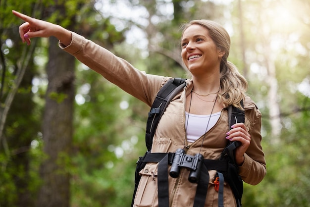 Hiking pointing or girl in nature forest or wilderness for a happy trekking adventure with freedom excited woman or hiker walking in a natural park or woods for exercise or holiday vacation view