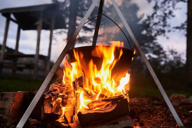 Hiking pot Bowler in the bonfire Fish soup boils in cauldron at the stake Traveling tourism picnic cooking cooking at the stake in a cauldron fire and smoke