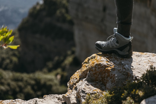 Hiking shoe stepping on a small rock with blurred landscape
background on sunny day copy space