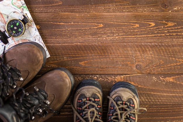 Hiking shoes with topo map and compass on a wood background.