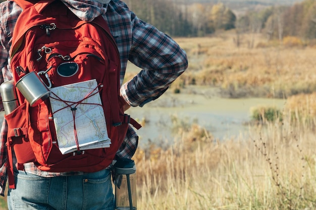 Photo hiking tourism cropped back view of man with backpack looking at swamp blur fall nature landscape background