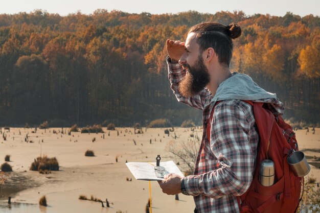 Photo hiking tourism side view of man using map and compass to explore country