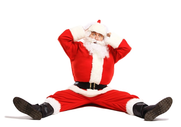 Hilarious and funny Santa Claus confused while sitting on a white surface full length