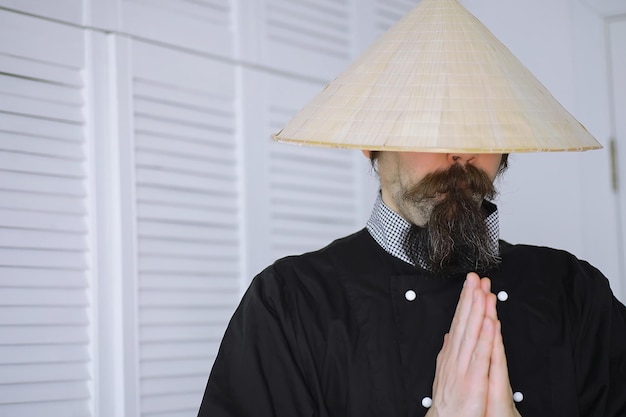 A hilarious parody of an Asian man in a Vietnamese hat with a beard Portrait Asian cafe chef