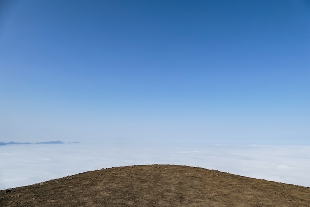사진 구름과 푸른 하늘을 배경으로 한 땅의 언덕