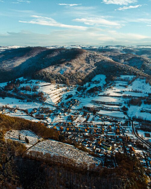 Photo hill with forest and snowy sunny fields behind village