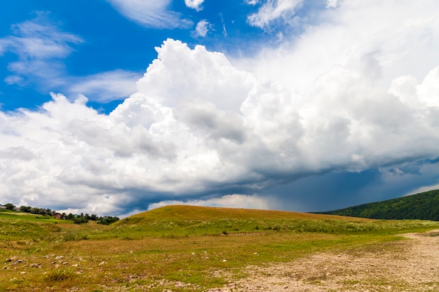 Hill with green grass and dramatic storm clouds overhead