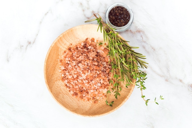 ヒマラヤピンクの塩顆粒木製皿とタイムトセマリーとコショウフードスパイスフラットレイ