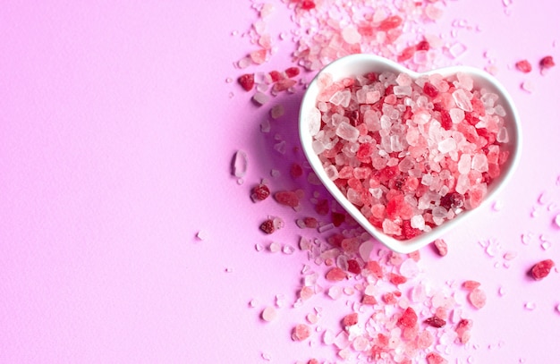 Himalayan pink salt on pink paper background in a heart shape saucer