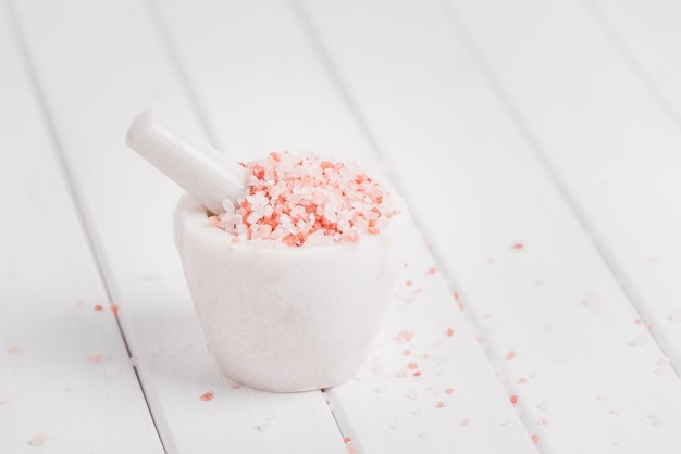 Himalayan pink salt in white marble mortar on hemp sack background. Himalayan salt commonly used in cooking and for bath products such as bath salts. Copyspace.