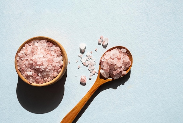 Himalayan pink salt in wooden spoon placed on blue background