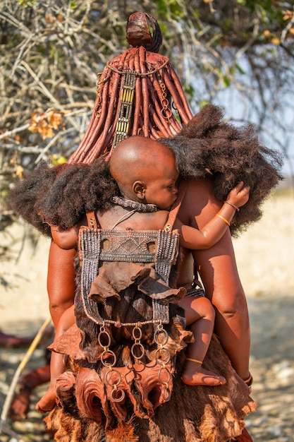 어머니의 등 뒤에 있는 Himba 아이.