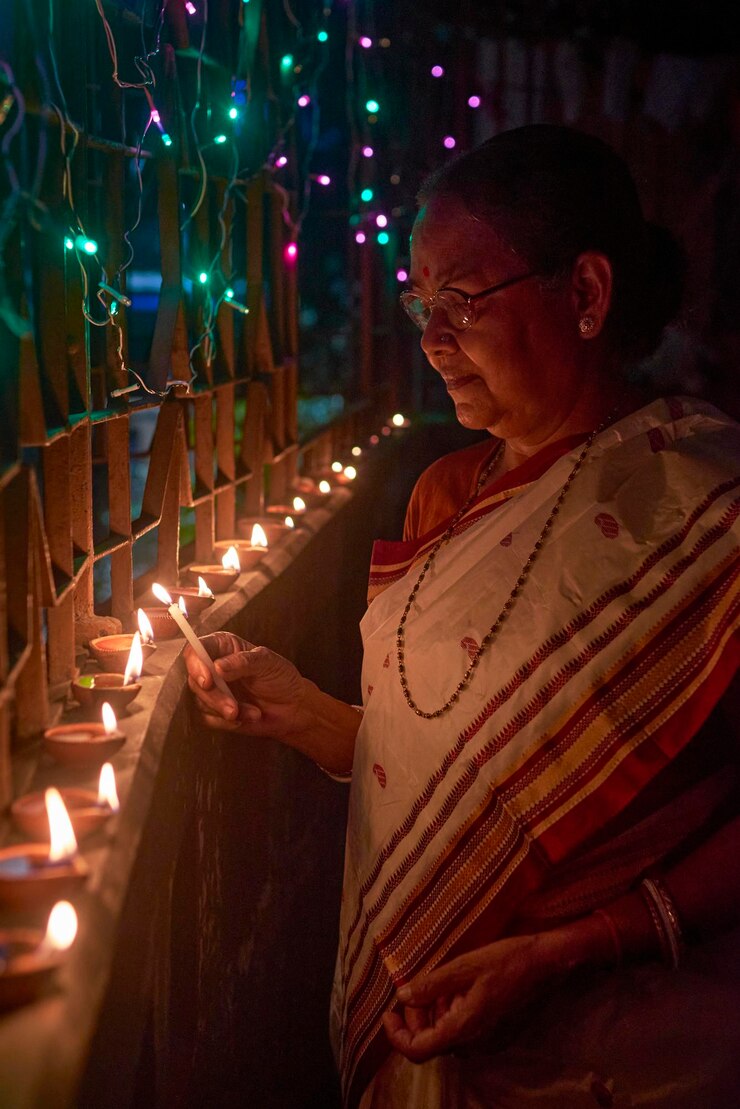 Photo a hindu woman decorating her home with diyas on the evening of diwali and kali puja