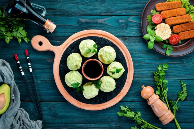 Hinkali with meat, spinach and soy sauce. On a wooden background. Top view. Free copy space.