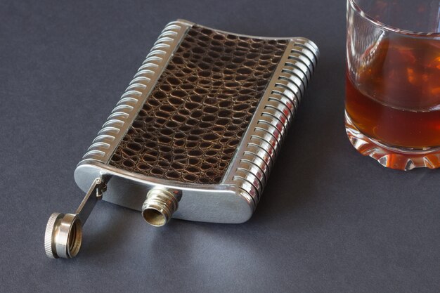 Hip flask  and glass on a black background