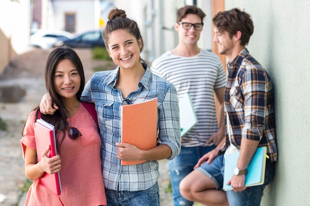 Hip friends holding notebooks and looking at the camera on the street