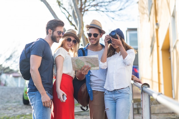 Hip friends taking pictures and checking map in the streets