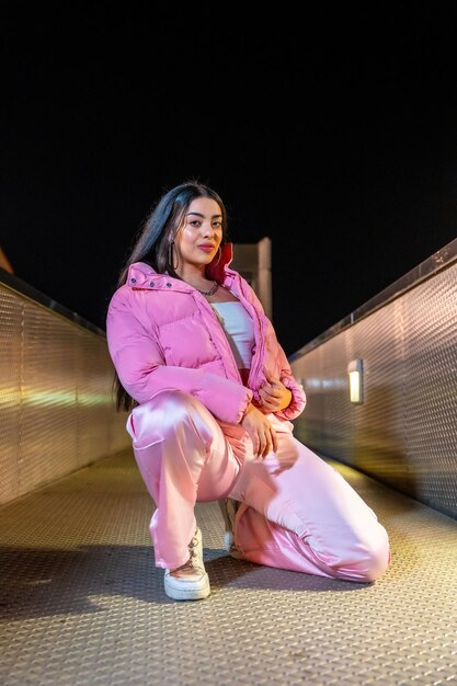 ピンクの服を着たヒップホップダンサーが夜に屋外でひざまずいている