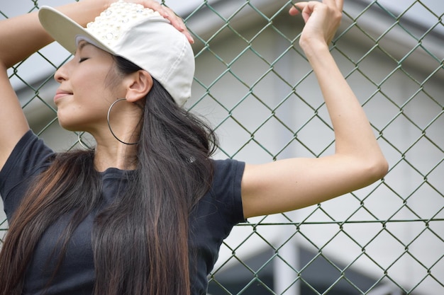 Photo hip-hop dancer wearing cap against fence