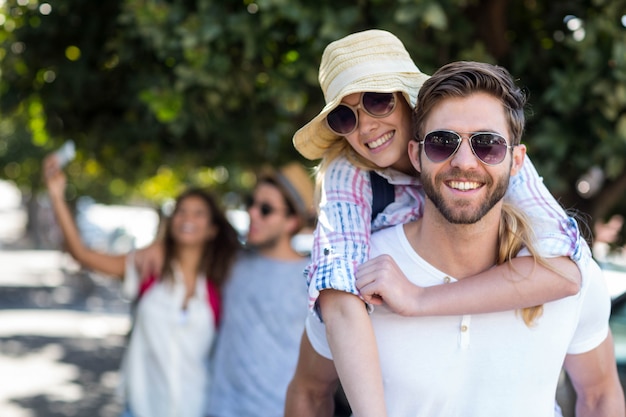 Hip man giving piggy back to his girlfriend on the street